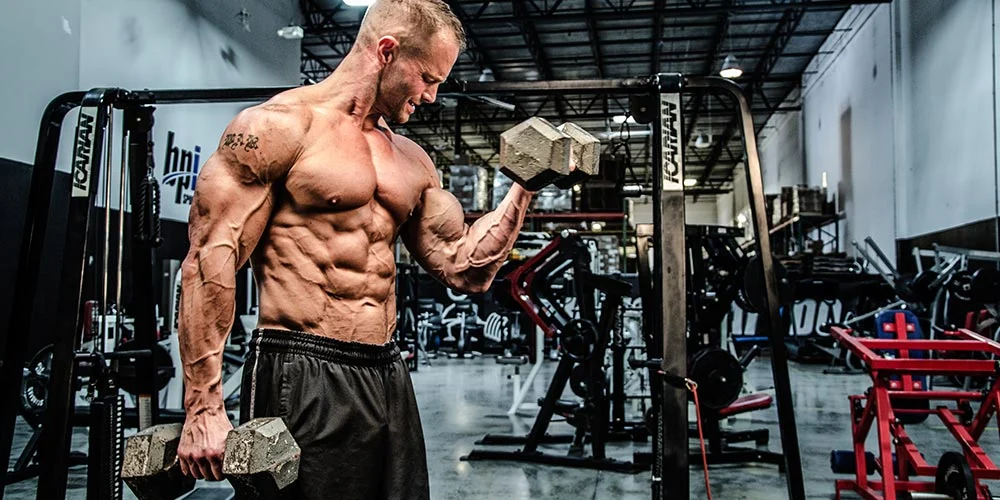 A muscular man lifting dumbbells with a focused expression, symbolizing bodybuilding and strength training.
