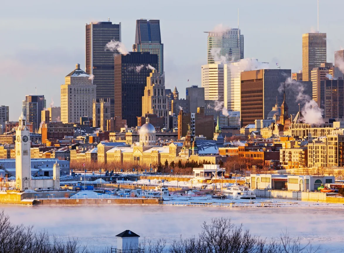 A scenic view of Montreal's skyline with smoke rising from buildings, highlighting the city's urban landscape in winter.