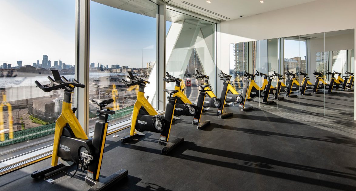A wide-angle shot of a spacious, well-equipped gym with rows of weight machines and free weights.